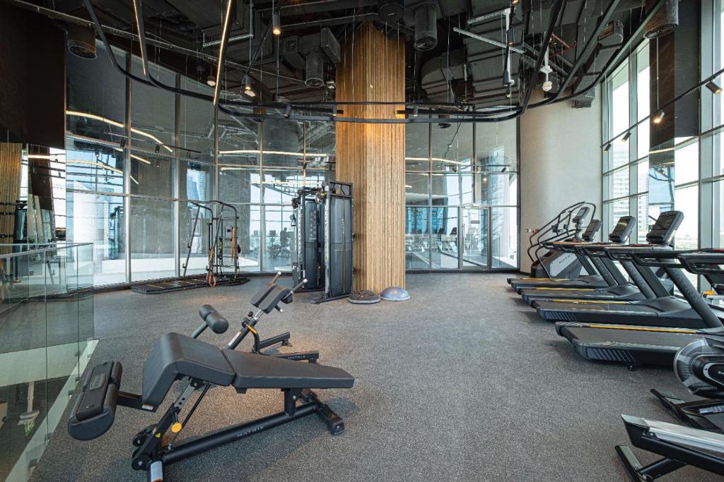 Indoor fitness center with treadmills and weight machines beside floor-to-ceiling windows