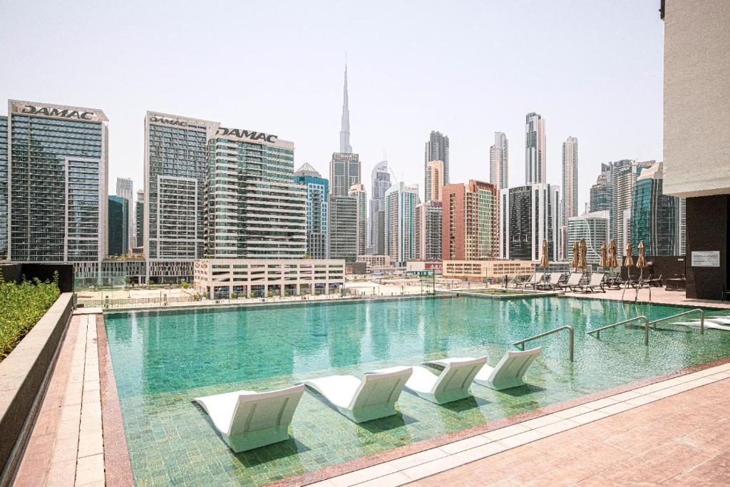 Rooftop infinity pool with loungers overlooking the Business Bay skyline by day