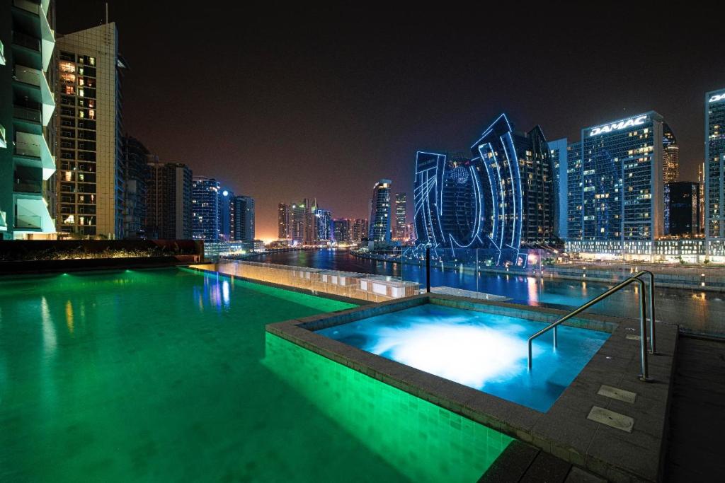 Rooftop pool and hot tub illuminated at night over the city