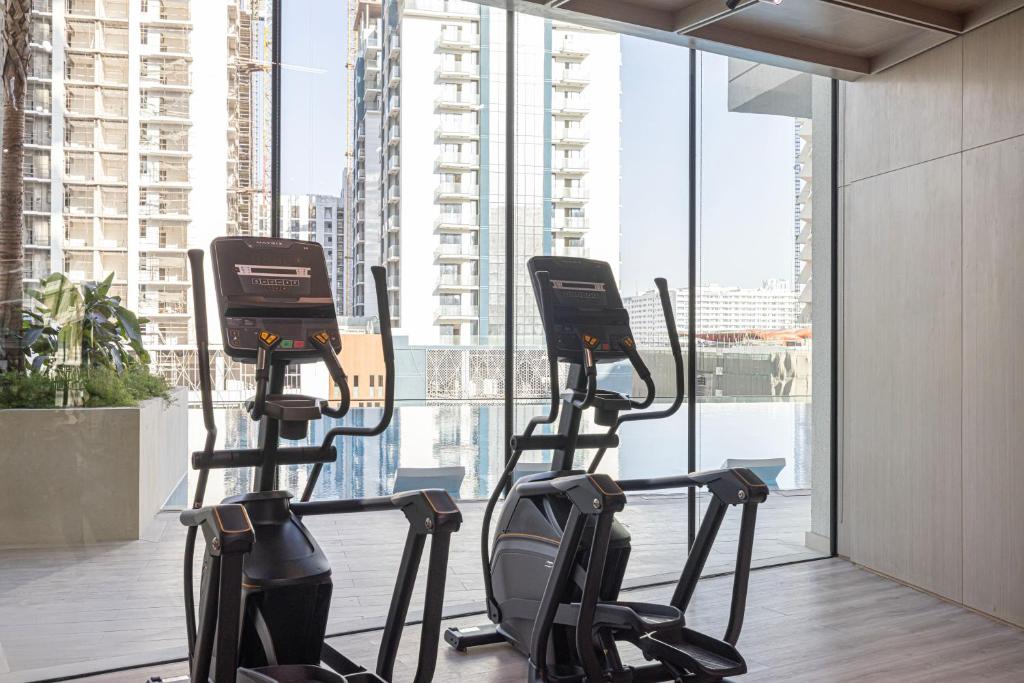 Cardio room with ellipticals facing floor-to-ceiling city and pool views