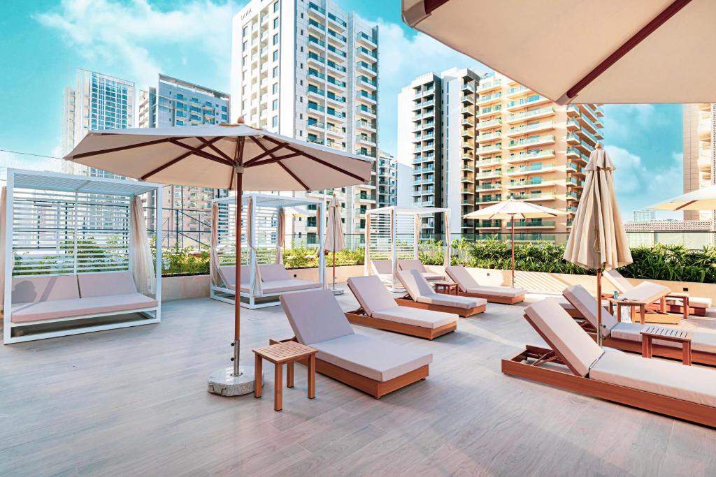 Rooftop pool deck with sun loungers, cabanas and umbrellas framed by towers