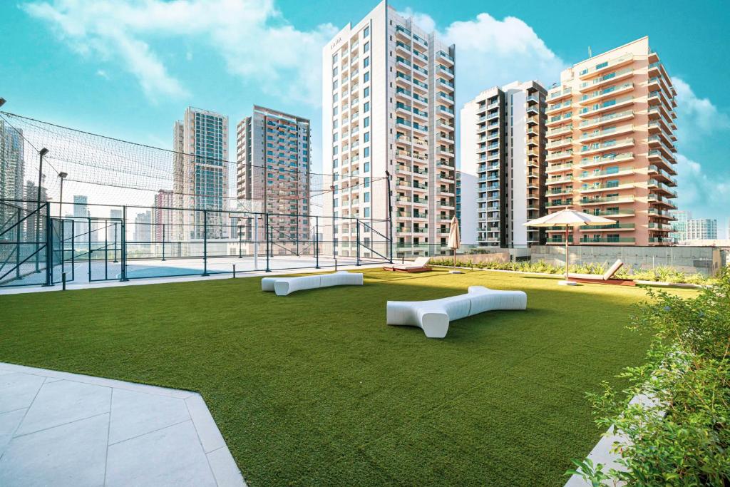 Landscaped rooftop lawn with sculptural benches and skyline views